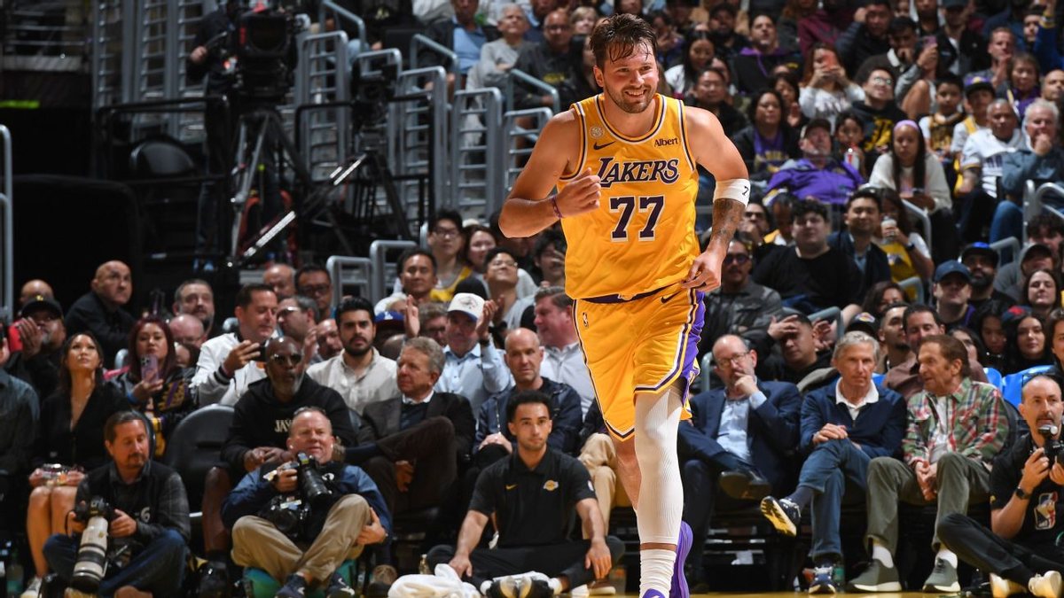 Luka Doncic runs up the court in a gold No. 77 Lakers uniform.